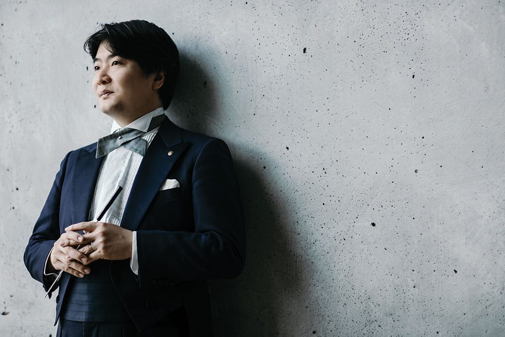 Kazuki Yamada in a tuxedo stands against a concrete wall