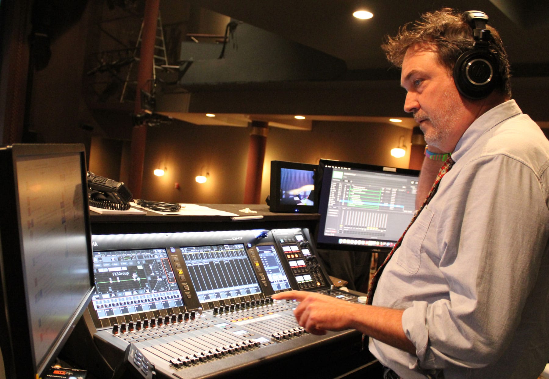 Rob Witmer stands with headphones on in front of a sound board working.