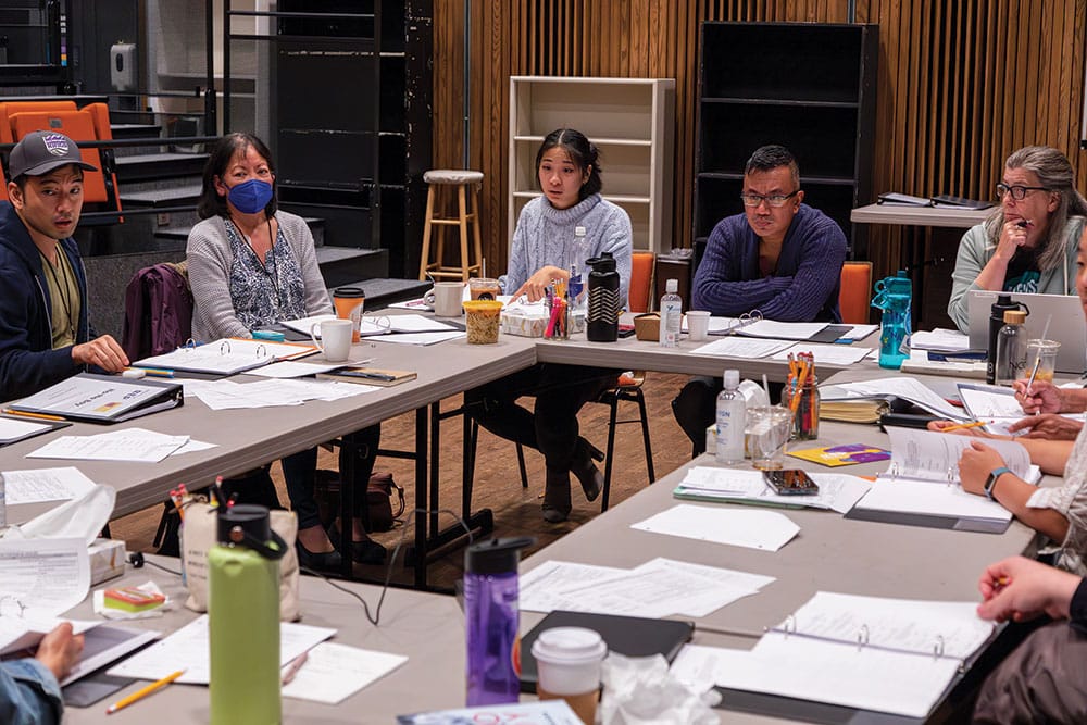 The Seattle Rep workshop cast of No-No Boy (2023) seated around tables.