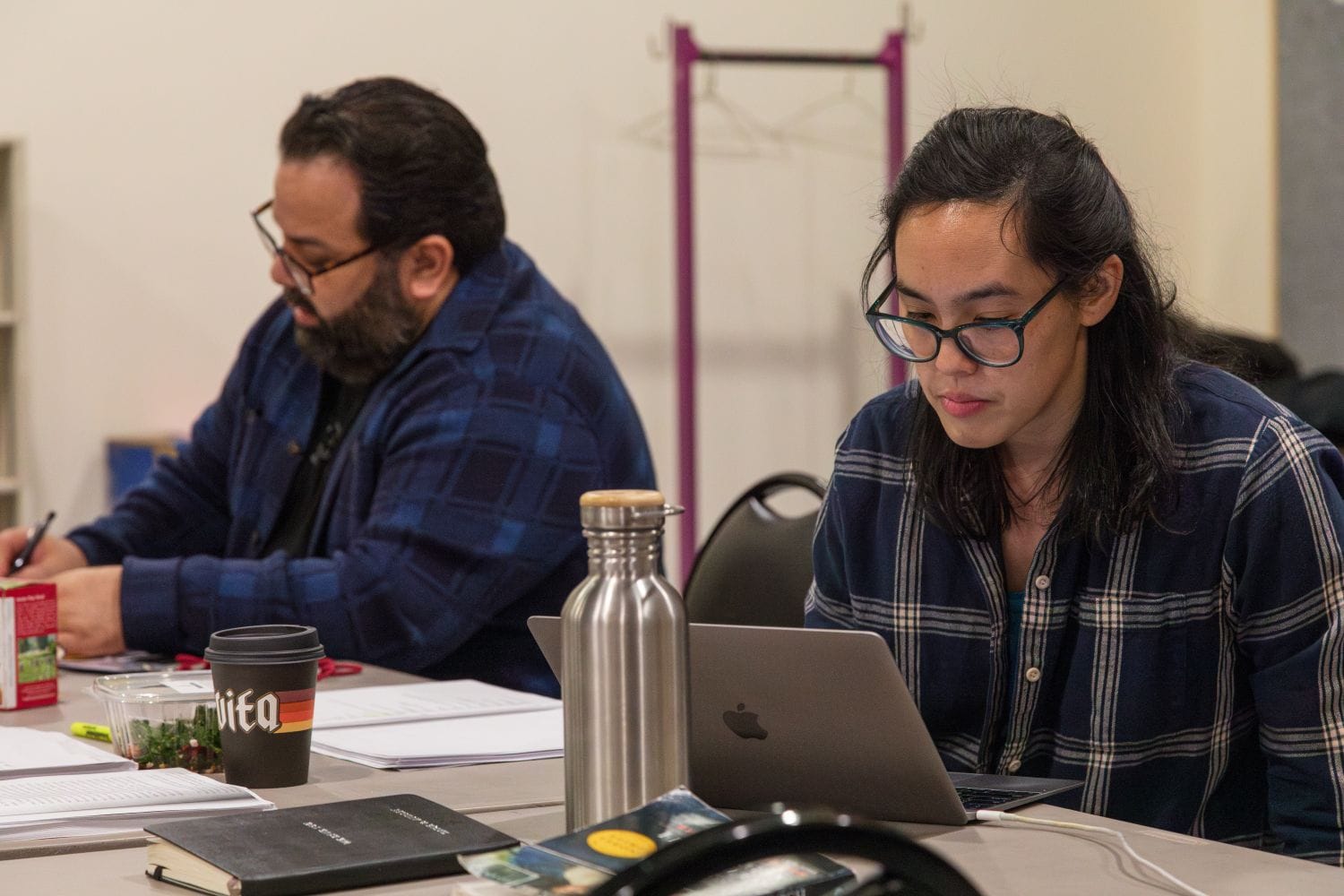 A director and a playwright sit at a table working side by side.