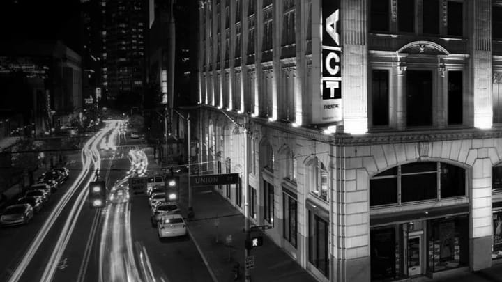 Black and white image of exterior of ACT Theatre's building with traffic in the background