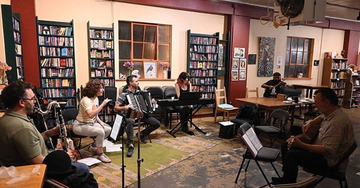 A group of musicians play together in a bookstore.