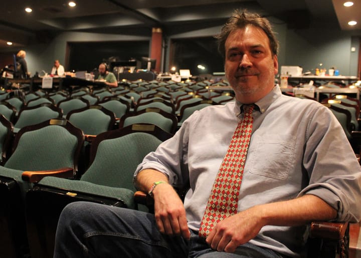 Rob Witmer sits in theatre seats looking at the camera with a slight smile.