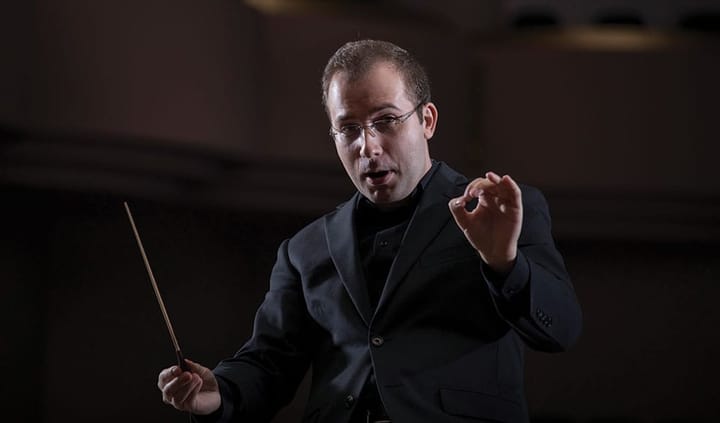 Radu Paponiu wears a black suit and holds a conductor's baton.