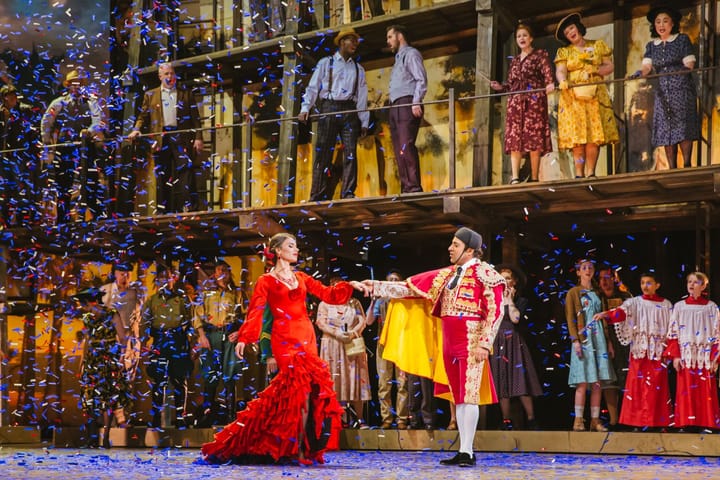 A woman in a red dress dances with a matador as confetti falls.