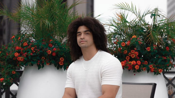 Composer Xavier Muzik sits in front of flowers looking at the camera.