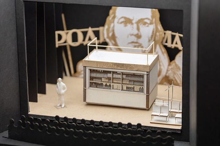 A model of a theatre with a stage that has a large face in the background and a stand at the forefront.